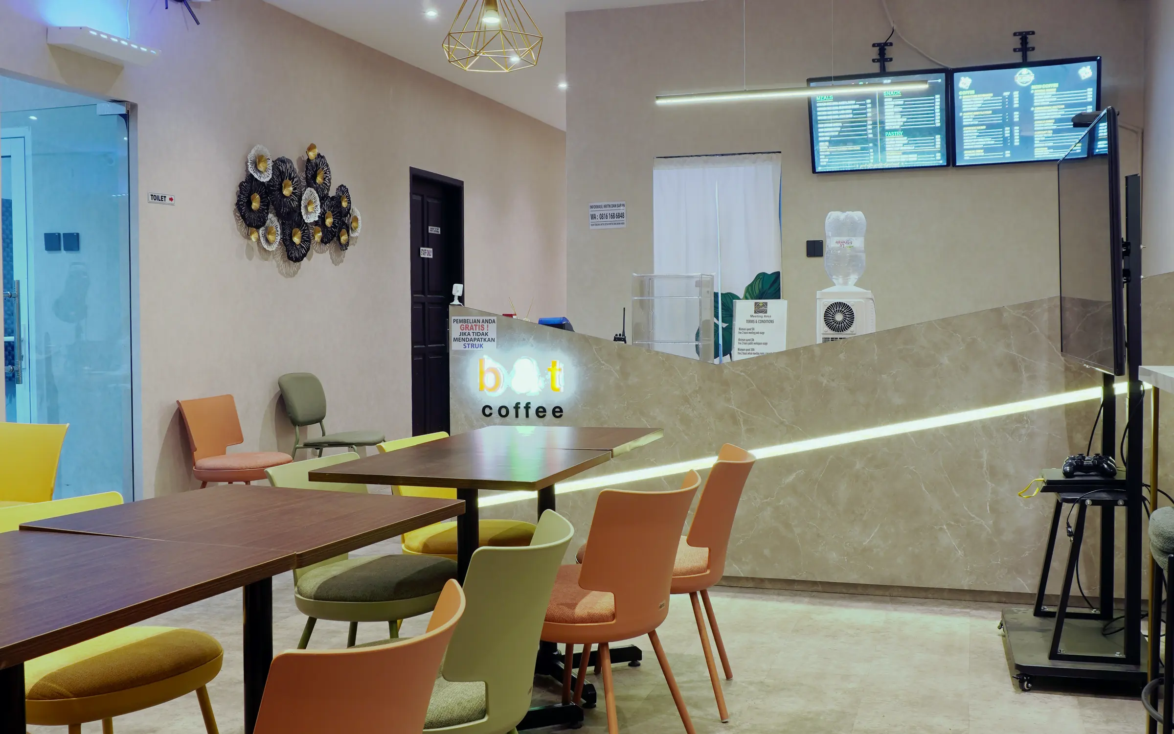 Ruang B and T Coffee dengan kursi oranye dan lampu gantung