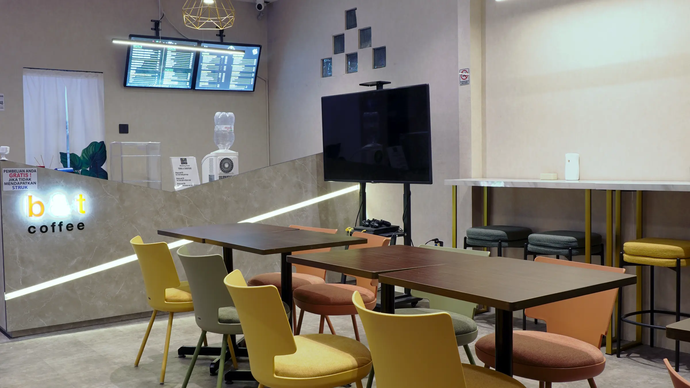 Sudut B and T Coffee dengan meja panjang dan layar menu