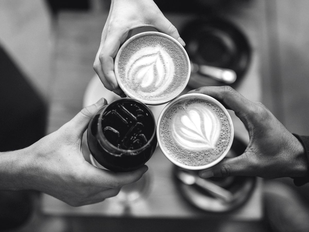 Tiga gelas kopi diangkat bersama di meja B&T Coffee